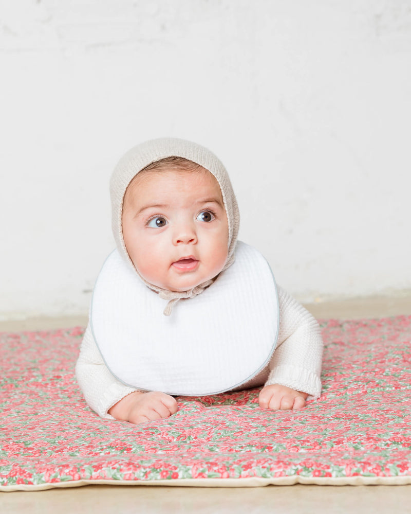 Bebé-con-babero-impermeable-blanco-pique