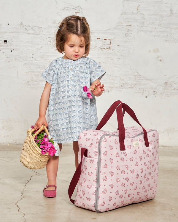 niña con maleta de maternidad  Anita flores rosas sobre fondo rosa